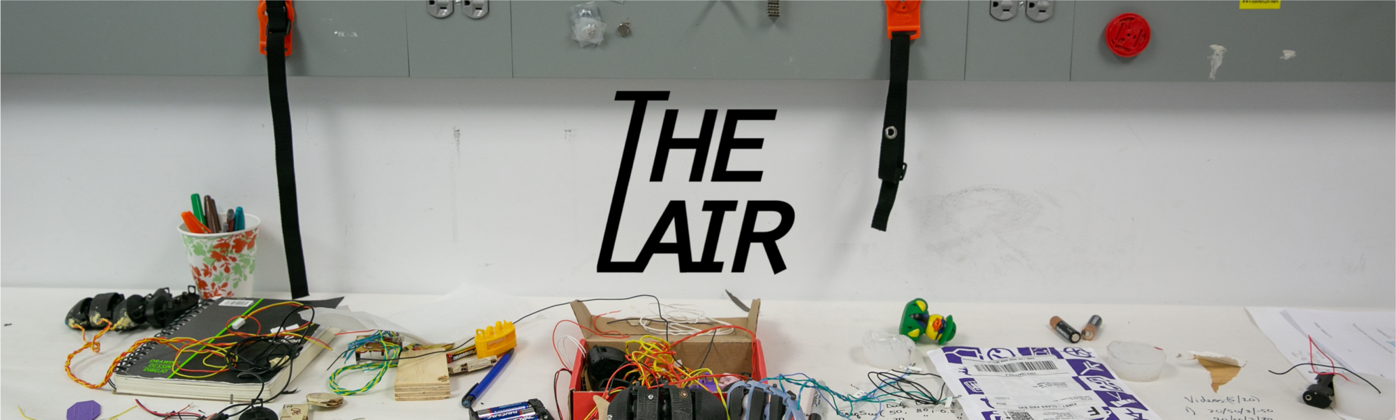 Banner with the Olin College LAIR logo, a stylized version of the words "The Lair," over a background of a cluttered lab bench.