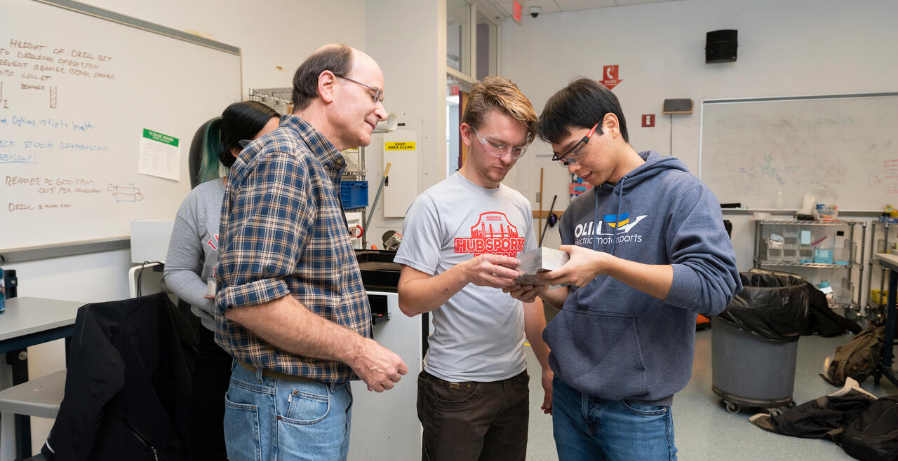 Professor Dave Barrett works in the Shop with two students.