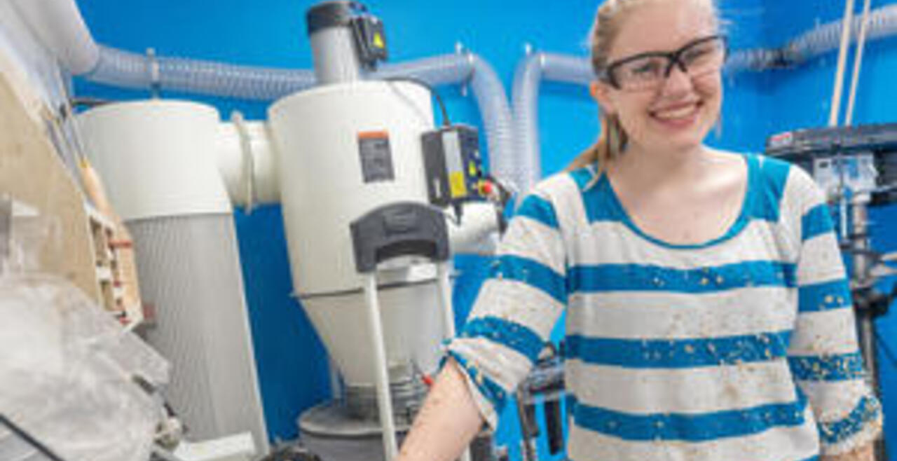 Student smiling at camera with wood chips on clothing